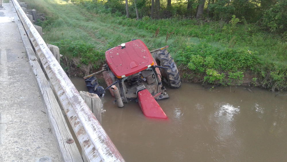 front view of red tractor partially in the water