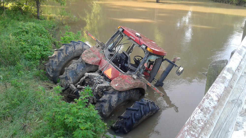 back end of red tractor partially in the water